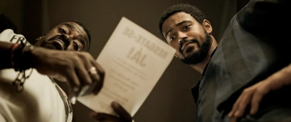 EXECUTIVE ORDER STILL 5 Seu Jorge left and Alfred Enoch scaled